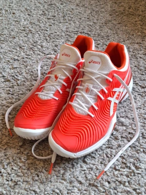 Asics Court FF Novak - Orange Tennisskor  - Asics Court FF Novak - Orange, Tennisskor i storlek 41.5 Knappt använda och skicket är i princip som ny. Riktigt snygga och sköna. Skick: 10/10