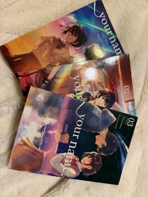 Your Name manga volym 1-3 - Säljer manga-serien 'Your Name' volym 1 till 3 med färgstarka omslag och animeinspirerad konst. Perfekt för dig som gillar romantik och övernaturliga berättelser. Böckerna är i pocketformat och har snygga illustrationer på framsidan.