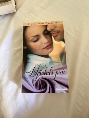 Hjärtats pris antologi - Romantisk antologi med fyra romaner i en bok, utgiven av Harlequin. Omslaget har en mjuk lila ton med ett närgånget par i fokus. Författare är Penny Jordan, Emilie Rose, Maureen Child och Katherine Garbera. Perfekt för dig som gillar kärleksromaner.