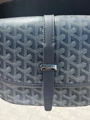 Grå axelremsväska i läder - Snygg grå handväska i slätt läder med magnetlås och innerfack med dragkedja. Väskan har en stilren design och är perfekt för dig som gillar minimalistiska accessoarer. Insidan är fodrad med ljust tyg i fiskbensmönster.