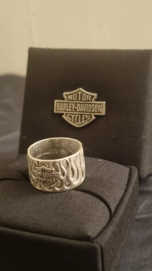 Harley-Davidson Ring Silver 925 Flames- RARE MOD Vintage Silver 925 flame Ring. US8 - Kopierade min ebay annons.  Up for sale is a genuine, collector-grade Vintage Harley-Davidson Flame Band. This is a heavy-weight, wide-band "open-cut" flame design crafted by MOD Jewelry, the premier official licensee for Harley-Davidson’s high-end sterling silver collections.  Unlike modern mass-produced stainless steel versions, this ring is solid .925 Sterling Silver with a deep, natural patina that makes the flame detail pop. This specific design is retired and increasingly difficult to find