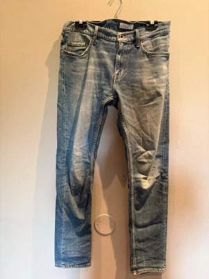 Ljusblå jeans från Tiger of Sweden - Säljer ett par ljusblå jeans från Tiger of Sweden med klassisk femficksmodell och snyggt slitna detaljer. Jeansen har raka ben och är tillverkade i ett mjukt denimtyg. Perfekta för en avslappnad och trendig look.