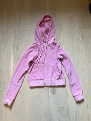 Y2k rosa hoodie  - Säljer en rosa hoodie från FB Sisters. Hoodien har dragkedja framtill, fickor och en huva med snören. På bröstet finns ett glittrigt märke i strass. 