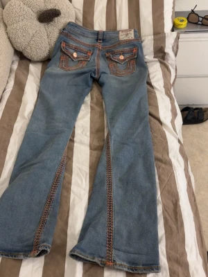 Low True Religion jeans - Säljer ett par blåa True Religion jeans med rosa och bruna sömmar. Köpte dom för 2300kr förra året och nu säljs dom inte längre. Jag är öppen för alla sorts frågor, även prissänkningar!💕