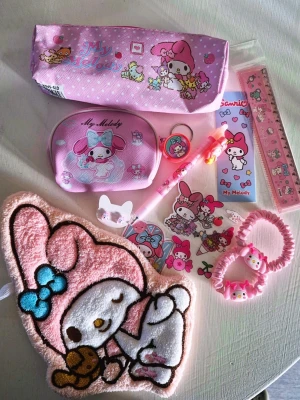 My Melody rosa paket 🩷 - My Melody rosa paket med blandade saker. Innehåller: Handduk, myntbörs, hårsnoddar, örhängen, pennfodral, klistermärken, linjal, penna, bokmärke och stämpel. 