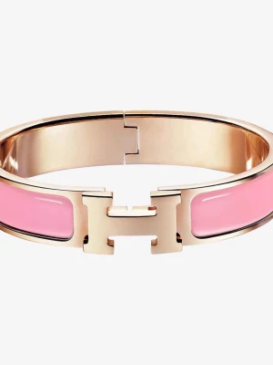 Rosa H-armband med gulddetaljer - Snyggt armband i metall med guldfärgad finish och rosa emaljpaneler. Armbandet har en tydlig H-detalj framtill som lås och är stilrent och trendigt. Perfekt accessoar för att lyfta din outfit med en färgklick och exklusiv känsla.