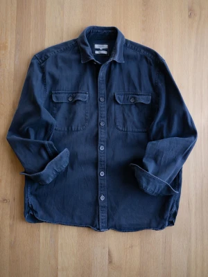 Mörkblå overshirt / hunting shirt med fickor - Stilren mörkblå overshirt från Jakers i mjukt bomullstyg. Två bröstfickor med lock och knappar, klassisk krage och knäppning framtill. Perfekt lager på lager-plagg för en avslappnad look.