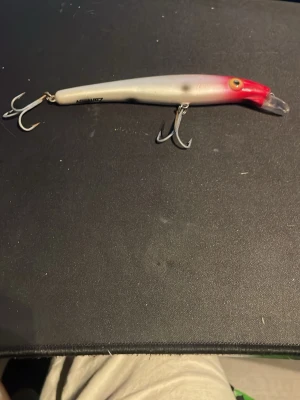 Zam Sv fiskedrag röd/vit - Säljer ett fiskedrag från Zam Sv i plast med två trekrokar. Draget är vitt med röd nos och har realistiskt öga. Perfekt för dig som gillar fiske och vill ha ett pålitligt bete i lådan.