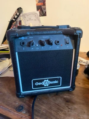 Gear4music GA-10 gitarrförstärkare - Säljer en kompakt svart Gear4music GA-10 gitarrförstärkare på 10W. Den har volym-, gain- och tonkontroller samt hörlursuttag. Perfekt för övning hemma eller i replokalen. Robust design med bärhandtag och tydlig logga på fronten.