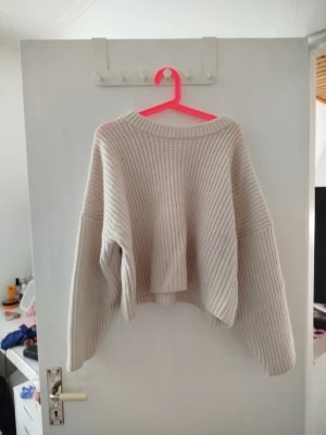 Beige oversized stickad tröja - Säljer en beige oversized stickad tröja med breda ärmar och ribbstickat mönster. Tröjan har en avslappnad passform och rund halsringning. Snygg till mycket och passar till allt. 