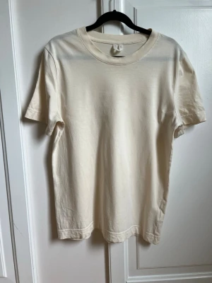 T-shirt - Arket - Beige / ljusgul t-shirt från Arket. Hemsidan kallar färgen ”light beige” men den drar lite åt ljusgult. Storlek XS. I mycket fint skick! 🌸