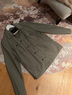 Olivgrön overshirt från Morris - Stilren olivgrön overshirt från Morris. Perfekt nu inför våren då den är tunn att ha över bara en t shirt, tjocktröja eller väst. Storleken är S men den är lite större i stl och passar exempelvis mig själv som har oftast har M på allt. Nypris ca 2000kr, mitt pris: 499kr. Hör av dig för frågor eller funderingar! 