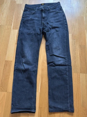 Svarta raka jeans från Lee - Snygga mörkblå jeans från Lee med rak passform och klassisk femficksdesign. Jeansen har en enkel look utan slitningar och är tillverkade i ett robust denimtyg. Perfekta för dig som gillar stilrena och tidlösa jeans.