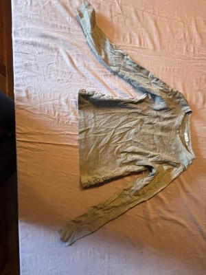 Ljusgrå stickad tröja med rund hals - En enkel och stilren ljusgrå stickad tröja med rund halsringning och långa ärmar. Tröjan har en rak passform och är tillverkad i ett mjukt, tunt stickat material som passar perfekt till lager på lager. Inga synliga loggor eller mönster.