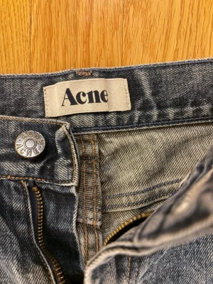 Acne Jeans - Snygga blå jeans från Acne Studios med klassisk rak passform och fem fickor. Jeansen har en diskret tvättad look och detaljer som silverfärgad knapp med logotyp. Jeansen är L34 men är kortare än vanliga 34, längden är 103cm och midjan 40cm. Tveka inte på att höra av dig vid funderingar! 