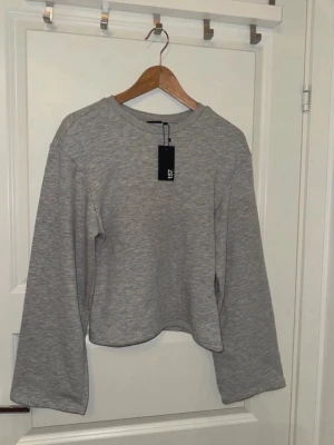 Grå croppad långärmad topp LST - Snygg grå croppad topp från LST med lång ärm och rund hals. Tillverkad i mjuk bomullsblandning som känns skön mot huden. Enkel och clean design som passar till allt. Perfekt att styla med jeans eller kjol för en chill look.