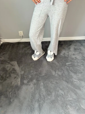 Ljusgrå mjukisbyxor med raka ben - Säljer ett par ljusgrå mjukisbyxor med raka ben och dragsko i midjan. Byxorna har resår i midjan och en bakficka. Perfekta för chill dagar hemma eller när du vill vara extra bekväm.