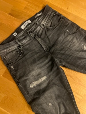 Grå Replay MICKYM Jeans LÄS BESKRIVNING - OBS Byxorna har hål och kommer behöva lagning, jag står inte för återbetalning. Säljer ett par grå jeans från Replay med slitningar och tvättade detaljer för en cool, avslappnad look. Modellen är smal och har klassiska fem fickor samt knappgylf. Perfekta för dig som gillar streetwear och en trendig stil. Storlek 28 32, Slim Tapered modell. Kan gå ned i pris vid snabb affär.