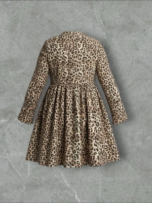 Leopardmönstrad långärmad klänning - Snygg kortklänning med leopardmönster i beige och svart. Klänningen har lång ärm, markerad midja och utställd kjol. Perfekt för dig som vill sticka ut med ett djurmönster. Tillverkad i mjukt tyg som ger en bekväm passform.