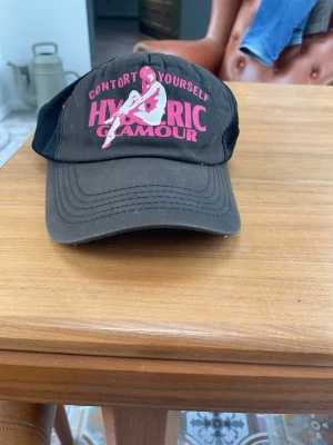 Hysteric glamour keps - Hysteric glamour keps ”contort yourself” Köpt på Grailed, enda paret på marknaden. Riktigt fet, one size, olivgrön front med rosa text och svart trucker 