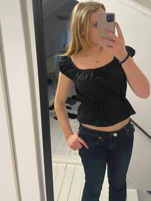 Svart croppad topp från H&M - Säljer en svart croppad topp från H&M med korta puffärmar och elastisk midja. Toppen har en söt spetskant vid halsringningen och är tillverkad i mjuk bomull. Perfekt för dig som gillar en trendig och bekväm stil. Jag har använt den 1 gång så den är nästan helt ny ❤️❤️