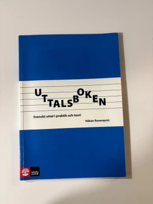 Uttalsboken - Svenskt uttal i praktik - Uttalsboken av Håkan Rosenqvist är en kursbok i blått och vitt mjukt omslag. Den tar upp svenskt uttal i teori och praktik och passar både nybörjare och avancerade. Boken innehåller övningar, metodik och lärarhandledning. Perfekt för dig som lär dig svenska.