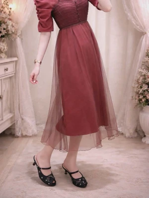 Vinröd långklänning med puffärm från Evelyn - Romantisk vinröd långklänning med transparent meshkjol och puffärmar. Klänningen har knappar framtill, markerad midja och en lätt volangkant nertill. Perfekt för dig som gillar en feminin och elegant stil.