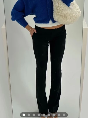 Svarta kostymbyxor med raka ben - Snygga svarta kostymbyxor med raka ben och låg midja. Byxorna har en klassisk passform och stilrena detaljer utan synliga fickor framtill. Perfekta för en clean och trendig look. Materialet ser ut att vara en mjuk och stretchig mix, vilket ger skön komfort.