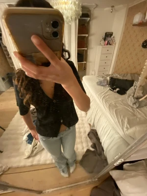 Svart v-ringad topp med knappar - Svart kortärmad topp med v-ringning och tre knappar framtill. Modellen är figurnära och enkel, perfekt att styla med jeans eller kjol. Materialet känns mjukt och stretchigt, troligen bomull eller polyester. Snygg basic som funkar till många looks.