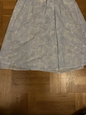 Ljusblå långkjol med mönster - Söt ljusblå långkjol med vitt abstrakt mönster. Klänningen har en luftig passform 