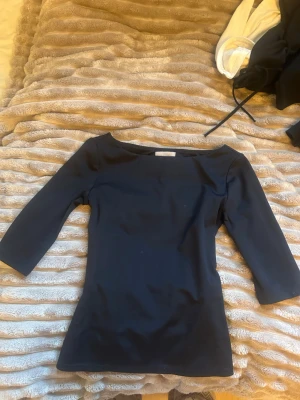 Svart topp med trekvartsärm från H&M - En stilren svart topp från H&M med trekvartsärm och rund halsringning. Toppen har en slim passform och är tillverkad i ett mjukt och stretchigt material som sitter snyggt på kroppen. Perfekt att matcha med både jeans och kjol.