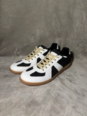 Maison Margiela Oreo gats  - Säljer ett par helt nya Maison Margiela Gats sneakers i den sällsynta “oreo” färgställningen (svart/vit). Modellen är från innan 2017 och tillverkas inte längre – väldigt svåra att få tag på idag. Allt på bilden följs med alltså box och dustbags. Pris kan diskuteras vid smidig affär.