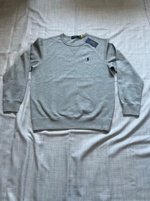 Ralph lauren crewneck grå strl M - Säljer en helt ny Ralph Lauren crewneck. Väldigt clean och stilren modell med perfekt passform. Enkel att matcha och fungerar året runt. Oanvänd i storlek M snabb frakt och bundlepris vid flera köp 