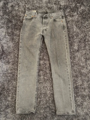 Grå 501:or från Levi's - Snygga grå jeans från Levi's med rak passform Jeansen har en vintagegrå tvätt och är tillverkade i kraftig denim. Perfekta för en avslappnad och trendig look. Storlek W30 L32