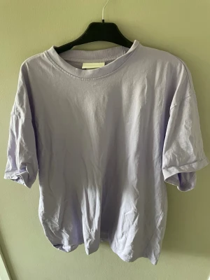 Ljuslila oversized t-shirt från H&M - Enkel och stilren ljuslila t-shirt från H&M i storlek L. T-shirten har klassisk passform med rund halsringning och korta ärmar. Perfekt för en avslappnad och trendig look.
