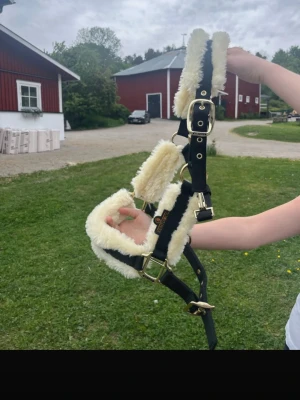Grimma från Kentucky🖤 - HELT NY🖤Nypris-814kr🔥 Säljer en svart grimma från Kentucky med mjuk, beige fluff och guldfärgade spännen. Grimman har justerbara remmar och är perfekt för att ge hästen extra komfort och stil. Märket syns tydligt på sidan. Passar till hästintresserade som vill ha något snyggt och bekvämt.