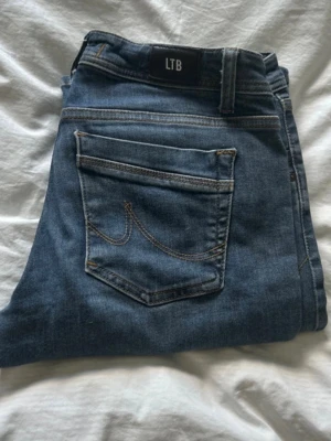 Blå jeans från LTB  - Säljer ett par klassiska blå jeans från LTB med snygga kontrastsömmar och en stor bakficka med dekorativ söm. Jeansen har låg midja och raka ben. Perfekta till en avslappnad stil och funkar året runt.