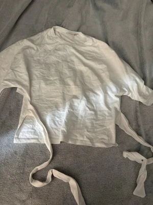 Vit topp med knytband!!💗 - Populär! vit topp med korta ärmar och långa knytband som kan knytas bak. Enkel och stilren design, perfekt att matcha med jeans eller kjol m.m från nelly använd max 2ggr!💗