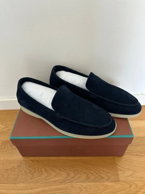 Loro Piana mörkblå mocka loafers - Snygga mörkblå loafers från Loro Piana i mjuk mocka med ljus sula. Modellen heter Summer Walk och har en stilren, minimalistisk design som passar perfekt till jeans eller chinos. Skorna levereras med originalkartong och dustbag. Passar folk med storlek 43-44! 
