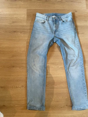 Ljusblå raka jeans  - Säljer ett par ljusblå jeans i klassisk rak modell med fem fickor och normal midja. Jeansen har en enkel, tidlös look utan slitningar eller dekorationer. Perfekta för en avslappnad stil.