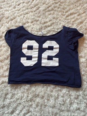 Mörkblå croppad t-shirt FB Sister - Mörkblå croppad t-shirt från New Yorker med stort vitt tryck av siffran 92 på framsidan. Endast använd några fåtal gånger!!