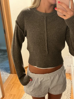 Mörkgrå cropped stickad tröja - Snygg mörkgrå/grön stickad tröja med croppad passform och markerad söm framtill från Designers Remix. Nypris runt 1,3k. Storlek S. Sitter som en XS/S. Lite nopprig men kan fixa det innan jag postar. Använd fåtal gånger