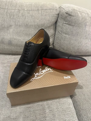 Svarta loafers från Christian Louboutin - Stilrena svarta loafers i läder från Christian Louboutin med klassisk design och ikonisk röd sula. Skorna har rundad tå, diskreta sömmar och låg klack. Perfekta för dig som vill ha en lyxig och tidlös look. Skorna är aldrig använda, och priset kan såklart diskuteras vid snabb affär