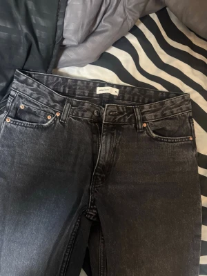 Svarta raka jeans från Gina - Säljer ett par svarta raka jeans f med klassisk femficksmodell. Jeansen har en tvättad look och är tillverkade i bomull. Perfekta för dig som gillar en avslappnad och trendig stil.