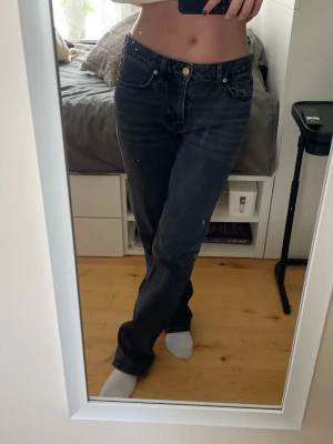 Svarta raka jeans med hög midja - Säljer ett par svarta jeans med raka ben och hög midja. Jeansen har klassisk femficksdesign och stängs med knapp och dragkedja. Perfekta för en avslappnad och trendig look.