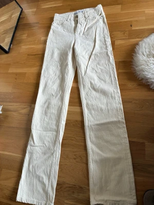 Zara Vita raka linnebyxor - Snygga vita linnebyxor med rak passform och klassisk midja. Byxorna har enkel design med fickor fram och bälteshällor. Perfekta för en avslappnad och stilren look. Materialet är luftigt linne som ger en skön känsla.
