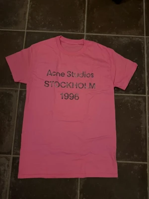 Rosa acne tshirt M - Riktigt fet och eftertraktad t-shirt med acne studios loggan i storlek M. Väldigt bra skick! Obs: Jag är lite osäker på äktheten då lappen i nacken saknas, därför säljs den billigare (499 kr, nypris ca 3000 kr). längd cirka 67cm, bredd cirka 47cm. Tveka inte att höra av dig vid frågor eller funderingar