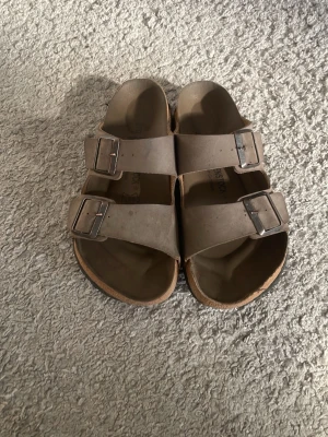 Beige Birkenstock sandaler med spännen - Snygga beige sandaler från Birkenstock. storleken passar nästan mig som har storlek 42,5, så ifall man storleken mellan 37-39 ish så kan dessa passa!