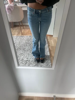 Ljusblå bootcut jeans  - Säljer ett par low waist bootcut jeans. Jeansen har klassisk femficksdesign, låg midja och lätt utsvängda ben. Snygga detaljer på bakfickorna och tillverkade i mjuk denim med lite stretch