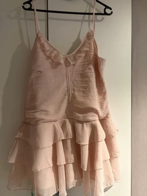 Sommarklänning - Super söt ljusrosa kortklänning från Divided med tunna axelband, volanger och v-ringning. Klänningen har ett lätt plisserat tyg och volangdetaljer både upptill och nertill för en romantisk look. Perfekt för varma dagar och somriga tillfällen. Köpt på Vinted med jätte fint skick o aldrig använd av mig 💗
